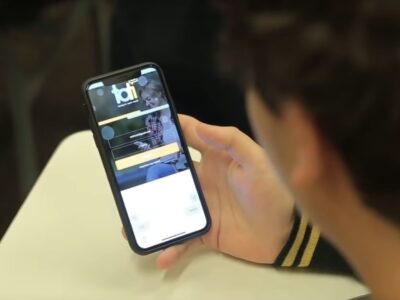 Estudante olhando o celular com o aplicativo Tati