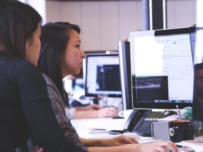 duas estudantes sentadas lendo no computador